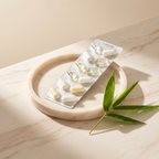 Packaged supplements on a marble surface with a bamboo leaf