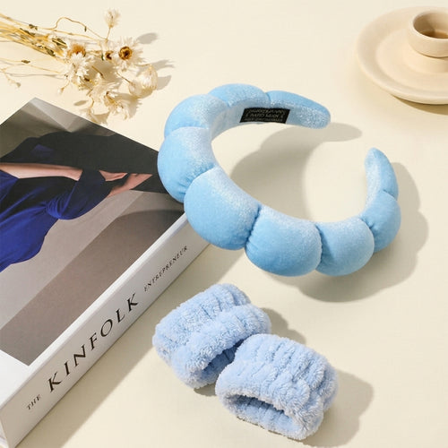 Light blue fuzzy eye mask and slippers on a beige surface with a book titled 'KINFOLK' in the background.