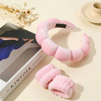 Pink plush dragon toy on a beige surface with a book titled 'KINFOLK' and decorative elements.
